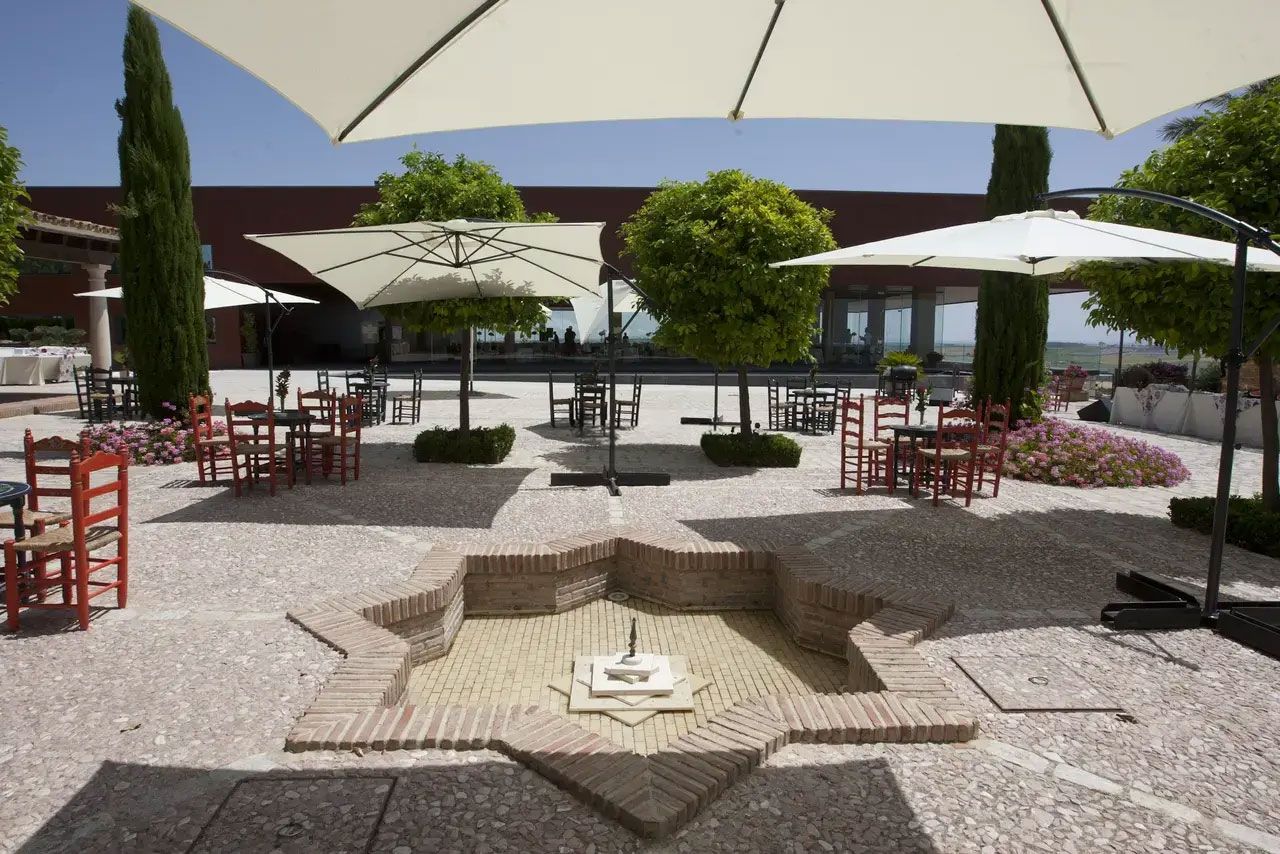 Courtyard with parasols, Andalusian chairs and a star-shaped brick fountain